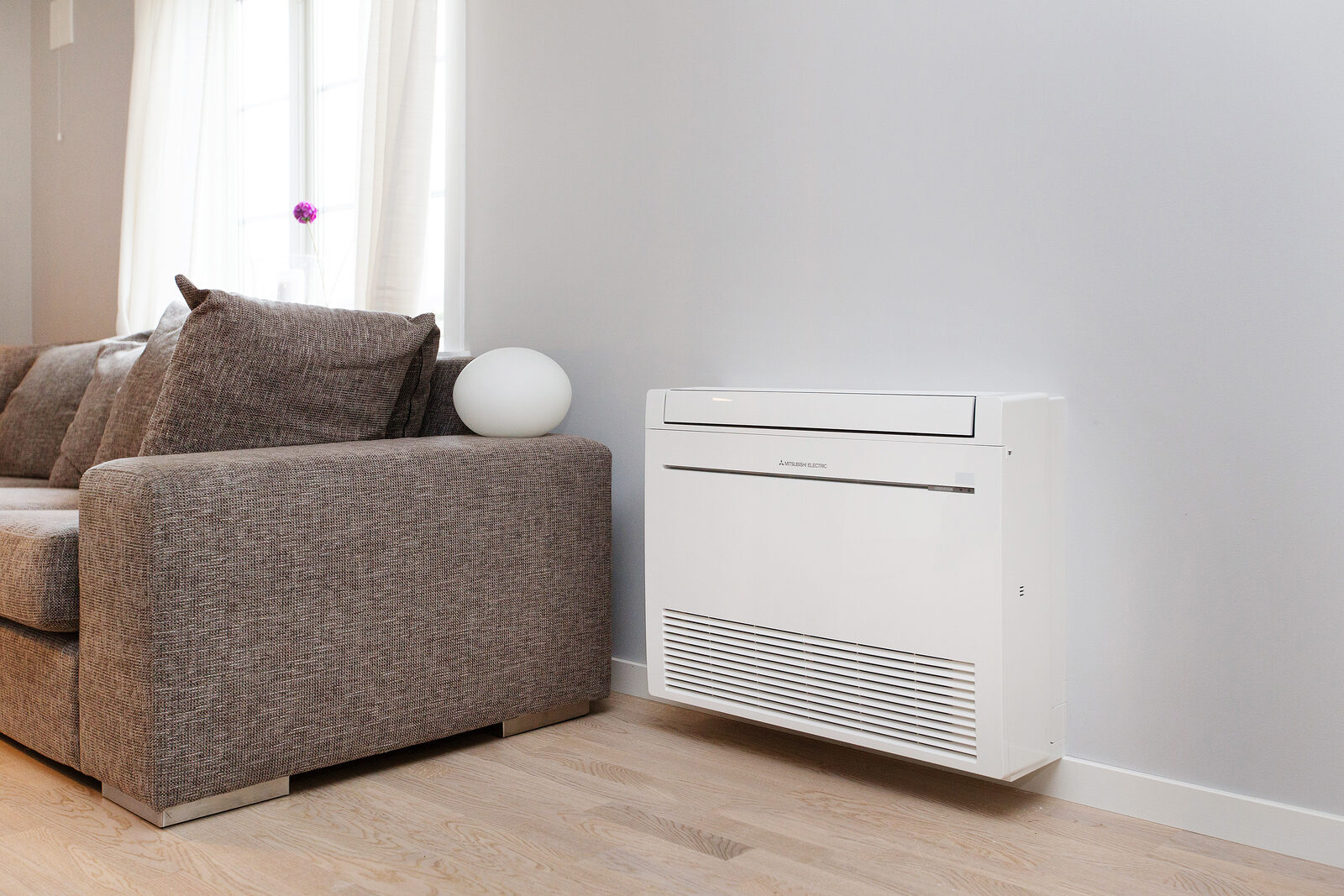 Varmepumpe som gulvmodell plassert ved sofa i stue